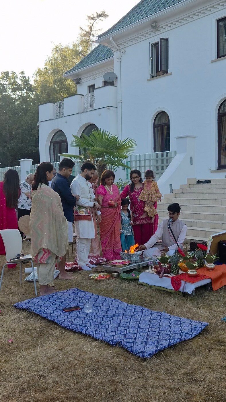 Family gathered on a lawn for a havan in front of a white house